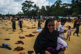 A Rohingya woman grips a bag of rice, while others search for food among donated articles of clothes. Pioneer Photo by Rahul Chakraborty.