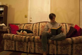 Dylan Brocker, 24, reads The Great Gatsby on his floral couch. Photo by Brandon King